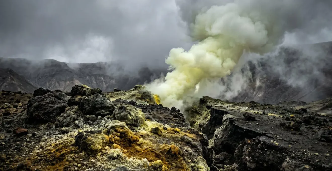 Émissions de vapeurs jaunes et verdâtres s'échappant d'une fracture volcanique avec roches sombres au premier plan
